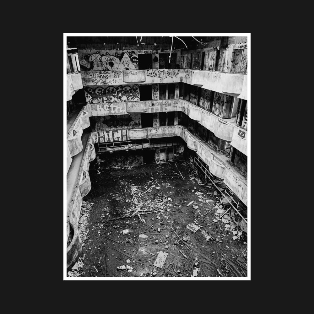 The crumbling interior of an abandoned hotel, with graffiti-covered walls and fractured surfaces, showcasing urban decay and raw desolation.